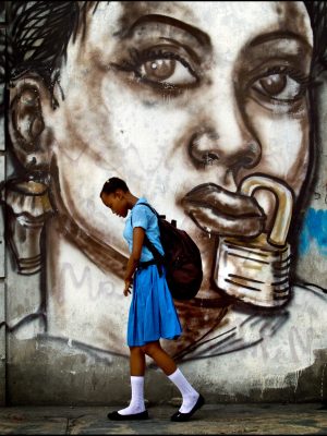 A student at a girl's school in Port-au-Prince walks past a mural by a famous Haytian street artist.